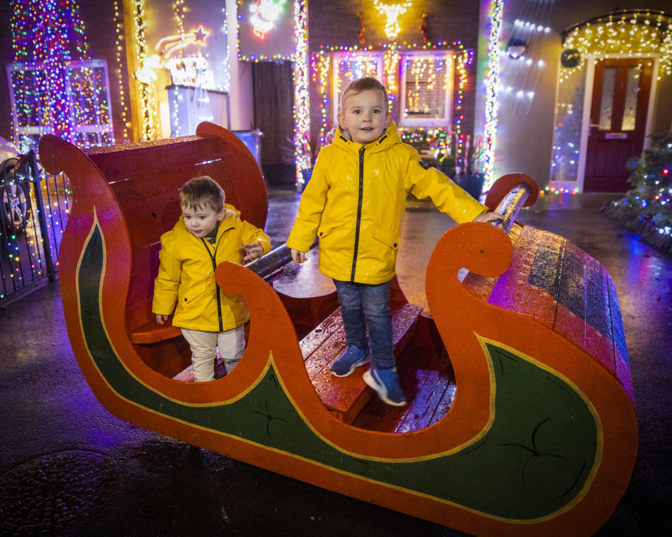 Three-year-old AJ Cairns and his one-year-old brother Teddy pose on Santa’s sleigh in Racecourse Drive (Liam McBurney/PA)