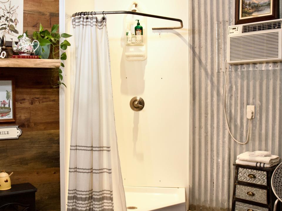 A shower stall with an open curtain in the middle of a room.