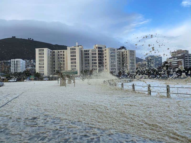 Strong wind and waves bring gusts of sea foam onto the shore in Cape Town