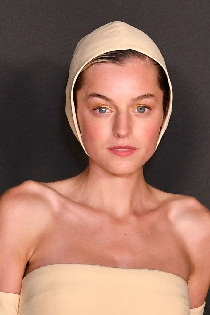 Actress Emma Corrin wearing a minimalist strapless outfit with a unique headpiece