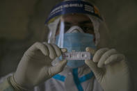 A health worker displays a test kit showing a positive result for COVID-19 in Gauhati, India, Friday, Sept. 18, 2020. India’s coronavirus cases jumped by another 96,424 in the past 24 hours, showing little sign of leveling. India is expected to have the highest number of confirmed cases within weeks, surpassing the United States, where more than 6.67 million people have been infected. (AP Photo/Anupam Nath)