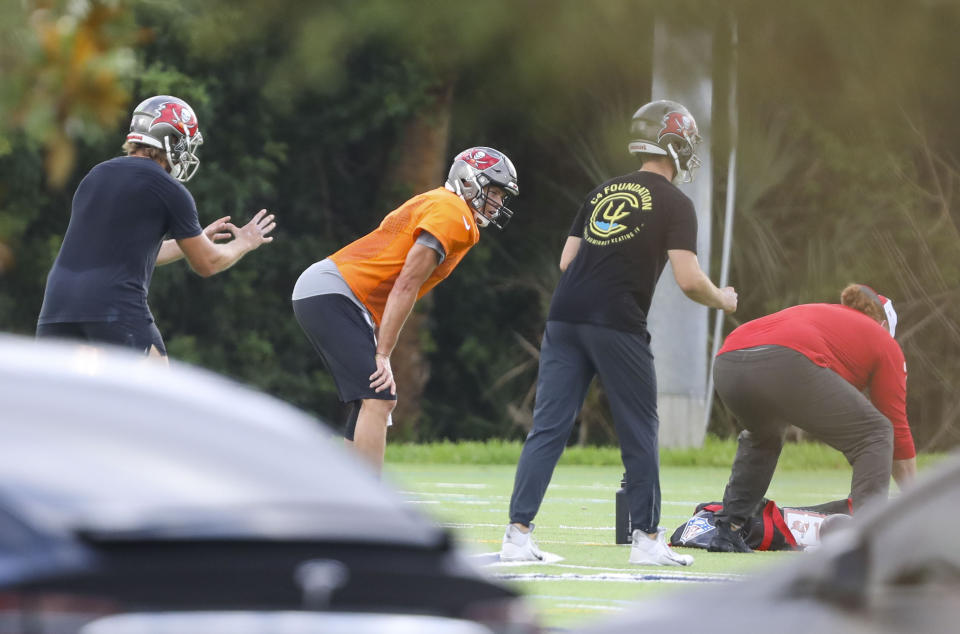 Tampa Bay Buccaneers NFL football quarterback Tom Brady, center in orange, is seen working out with other players at Berkeley Preparatory School in Tampa, Fla., Tuesday, May 19, 2020. (Chris Urso/Tampa Bay Times via AP)