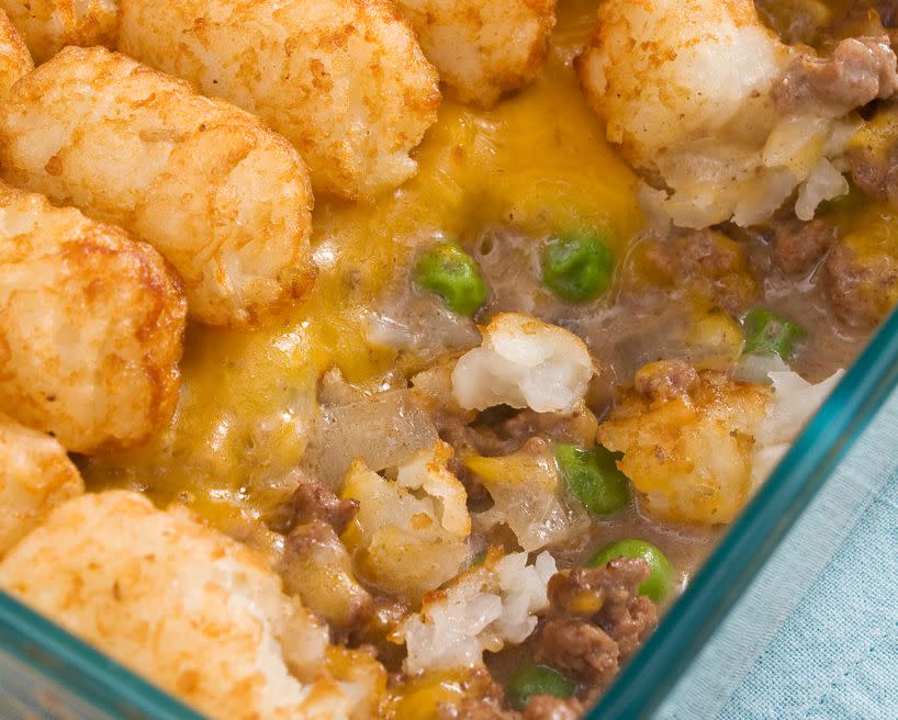 Casserole made of tater tots, cheddar cheese, ground beef, peas, and onions.