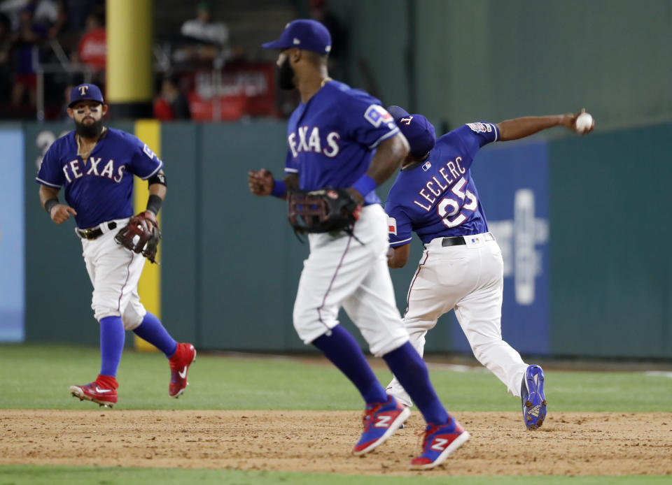 Texas Rangers' Rougned Odor, rear, and Danny Santana, front, jog to join the team in celebration as relief pitcher Jose Leclerc throws a ball following the team's 5-4 win against the Detroit Tigers in a baseball game in Arlington, Texas, Friday, Aug. 2, 2019. Leclerc threw the ball after covering first for the final out of the game. (AP Photo/Tony Gutierrez)