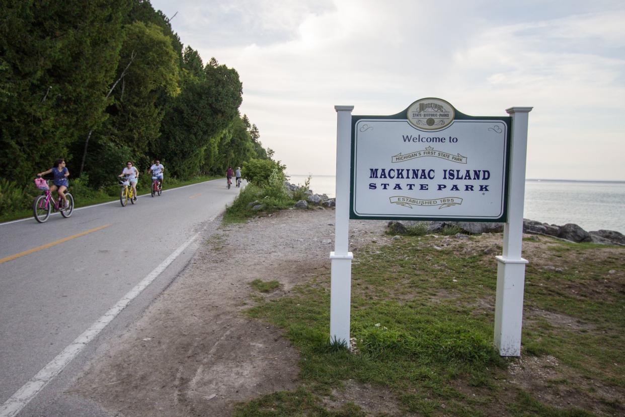 Mackinaw Island, Michigan, USA - August 8, 2018: Cyclists on Mackinaw Island coastal highway M-185. The island has a ban on automobiles so highway travel is limited to bike, horse and foot traffic.