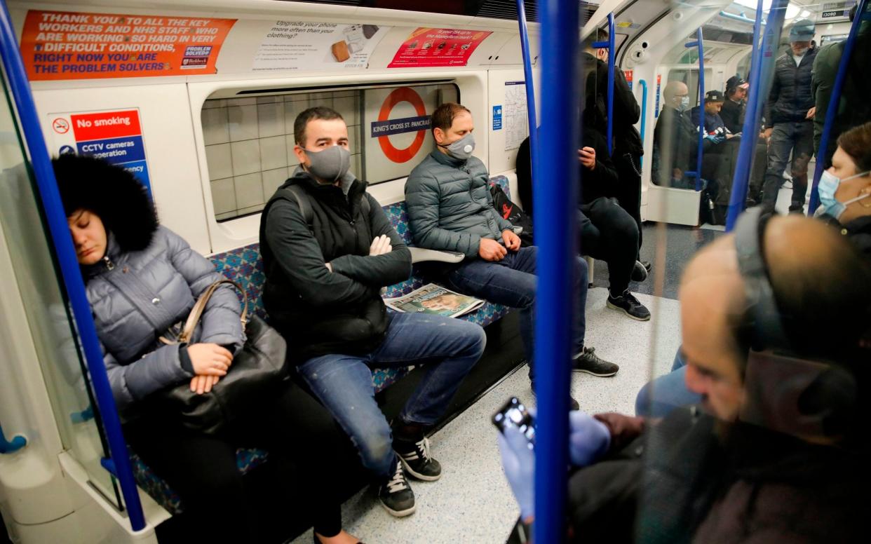 Passengers with and without face masks on a Victoria Line underground train in London - TOLGA AKMEN/AFP