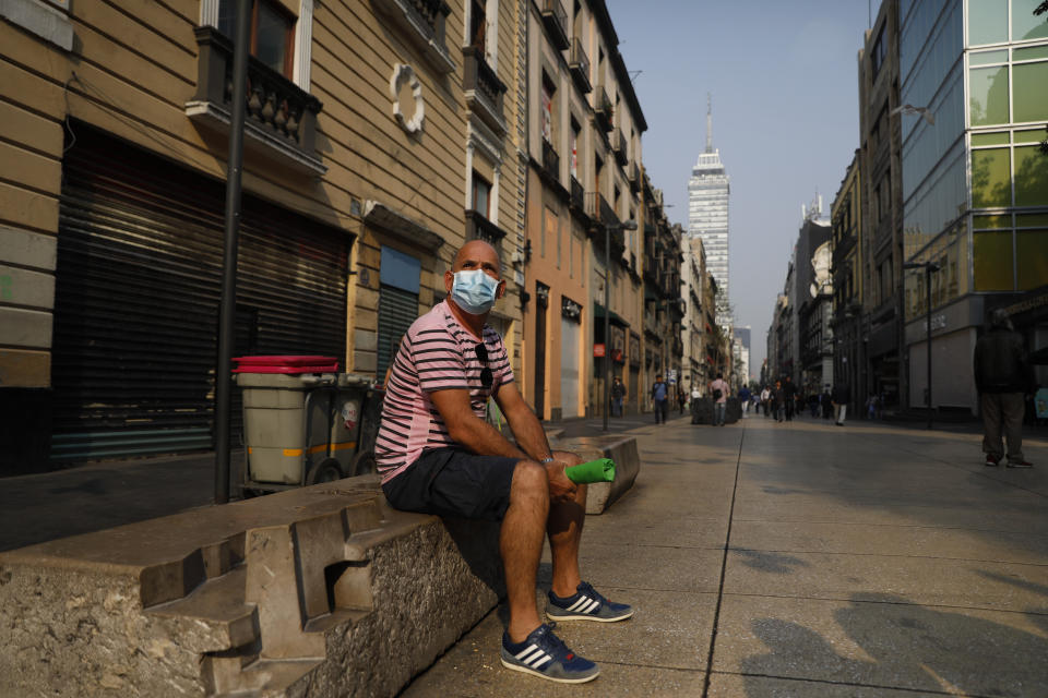 Cuban tourist Fernando Castillo wears a face mask as he sits on a bench on pedestrian Madero Street in the historic center of Mexico City, Thursday, May 16, 2019. Castillo and the three Cuban friends he is traveling with have all opted to use face masks while visiting the Mexican capital during a siege of air pollution that has led to the closure of schools and the cancellation of major sporting events. (AP Photo/Rebecca Blackwell)