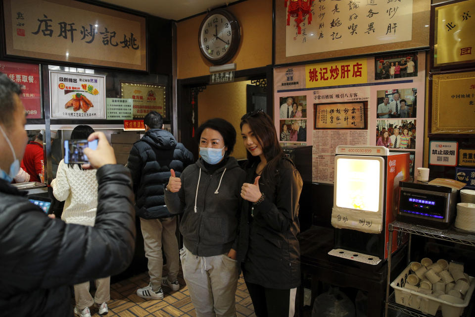 Customers pose for a souvenir photo with Joe Biden's photos on display in the background at a restaurant where he visited in 2011 as U.S. vice president, in Beijing, Sunday, Nov. 8, 2020. World leaders congratulated U.S. President-elect Biden on his victory, cheering it as an opportunity to fortify global democracy and celebrating the significance of Americans having their first female vice president. (AP Photo/Andy Wong)