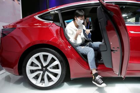 FILE PHOTO: A woman sits in a Tesla Model 3 car during a media preview at the Auto China 2018 motor show in Beijing, China April 25, 2018. REUTERS/Jason Lee/File Photo