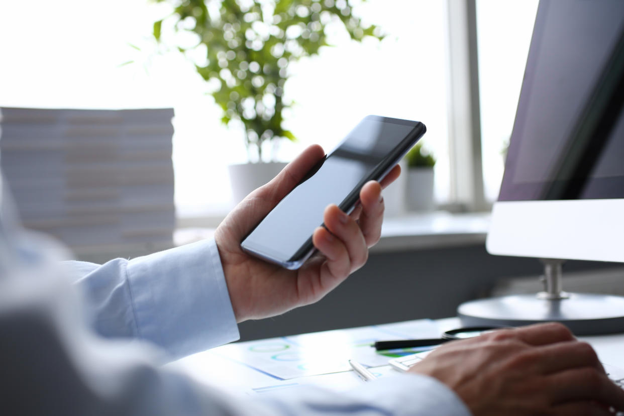 Businessman hipster holds telephone background of computer keyboard in office clodeup. Make transaction money mobile wallet cryptocurrency payment for goods services remote access management concept