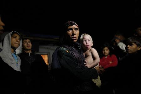 Bulgarian Roma Sashka Ruseva (C), 38, holds her son Atanas, 2, as she speaks to media outside her house in the town of Nikolaevo, some 280km (173miles) east of Sofia October 24, 2013. Bulgarian police have identified a couple they suspect are the natural parents of a blonde girl found in a Roma camp in Greece, and prosecutors are investigating the woman for selling her child, officials said on Thursday. Last week's discovery of four-year-old Maria sparked a global search for her real parents after DNA tests showed the Roma couple she was with were not her blood relatives. Bulgarian police questioned Ruseva and her husband, Atanas Rusev, 36, on Thursday in the southern town of Nikolaevo. REUTERS/Stoyan Nenov