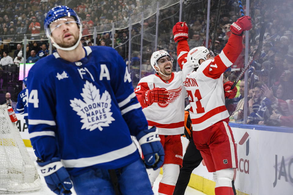 Detroit Red Wings center Dylan Larkin (71) celebrates after his goal with teammate left wing David Perron (57) as Toronto Maple Leafs defenseman Morgan Rielly (44) skates past during third-period NHL hockey game action in Toronto, Ontario, Sunday, April 2, 2023. (Christopher Katsarov/The Canadian Press via AP)