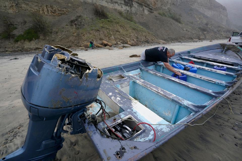 Boat salvager Robert Butler picks up a canister in one of two boats sitting on Blacks Beach on March 12, 2023, in San Diego.