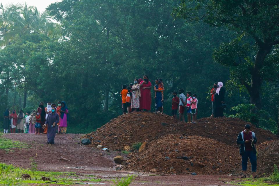 People gather to watch the wreckage of an Air India Express jet at Calicut International Airport in Karipur, Kerala, on August 8, 2020. - Fierce rain and winds lashed a plane carrying 190 people before it crash-landed and tore in two at an airport in southern India, killing at least 18 people and injuring scores more, officials said on August 8. (Photo by Arunchandra BOSE / AFP) (Photo by ARUNCHANDRA BOSE/AFP via Getty Images)