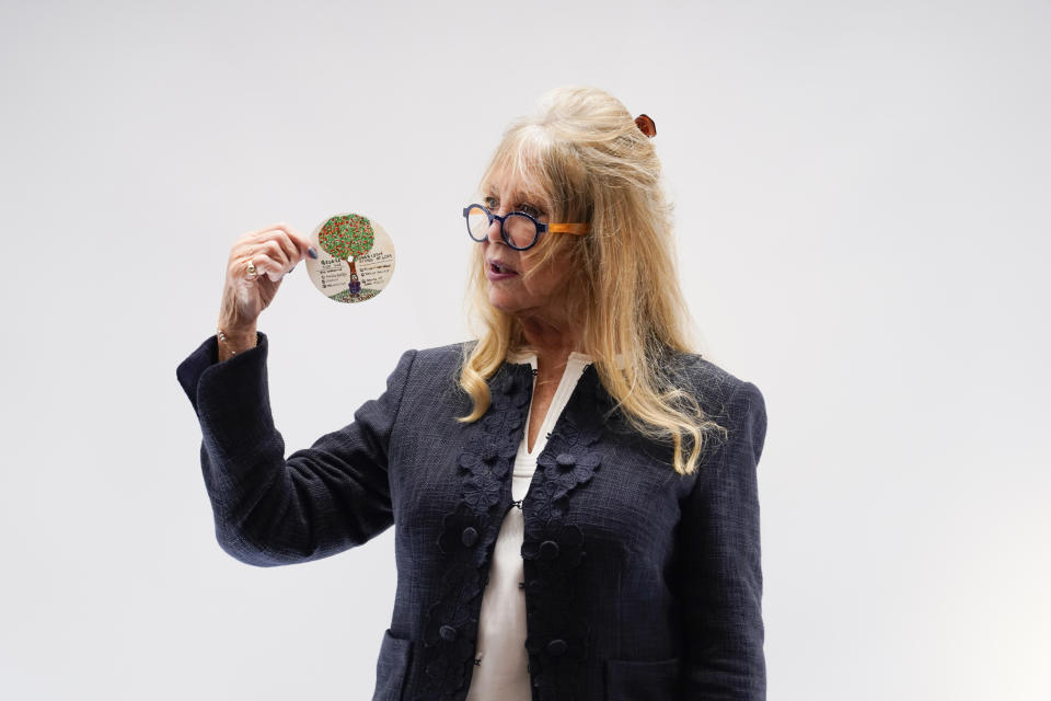 Pattie Boyd holds an original designed doodle by George Harrison as part of The Pattie Boyd Collection at Christie's, in London, Thursday, March 14, 2024. The doodle is estimated to sell £3,000-5,000. (AP Photo/Alberto Pezzali)