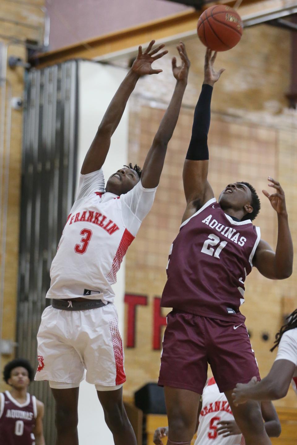 Aquinas's Christopher Leysath tips a rebound away from Franklin's Terence Thompson as they battle under the basket.