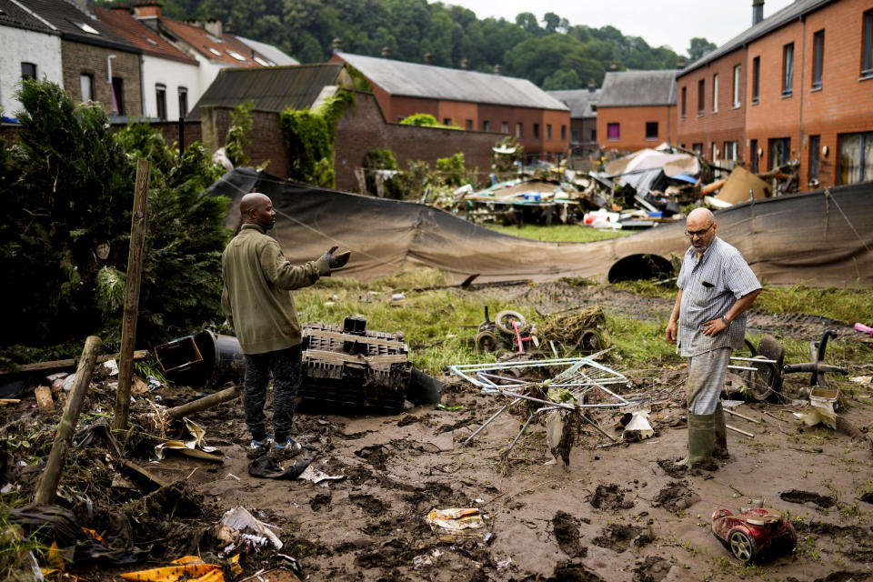 Image: Two residents speak with each other as they clean up after flooding in Ensival, Verviers, Belgium, on July 16, 2021. (Francisco Seco / AP)