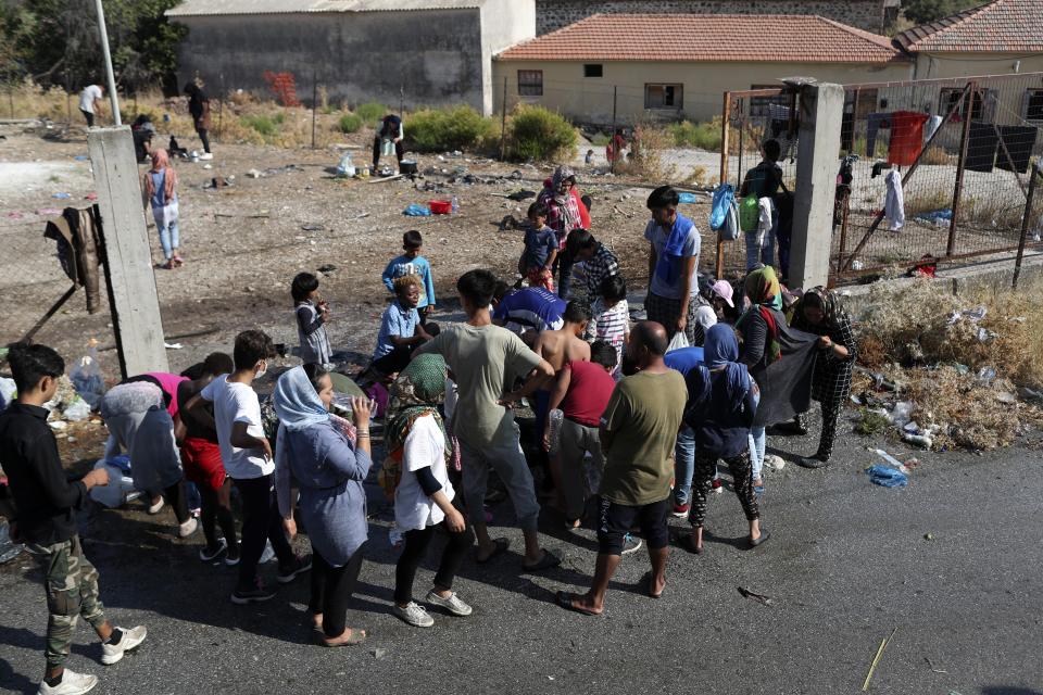 Migrants cook on the roadside near Mytilene town, on the northeastern island of Lesbos, Greece, Saturday, Sept. 12, 2020. Thousands of asylum-seekers spent a fourth night sleeping in the open on the Greek island of Lesbos, after successive fires destroyed the notoriously overcrowded Moria camp during a coronavirus lockdown. (AP Photo/Petros Giannakouris)