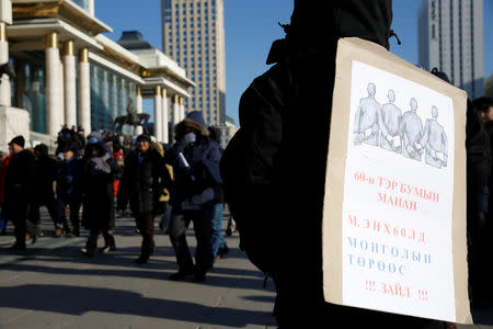 A protester carries a sign during a demonstration to demand the resignation of Mongolia's parliamentary speaker Enkhbold Miyegombo, at Sukhbaatar Square in Ulaanbaatar, Mongolia December 27, 2018. The sign reads, "MANAN of the 60 billion. Enkhbold, get out from the Mongolian parliament!" REUTERS/B. Rentsendorj