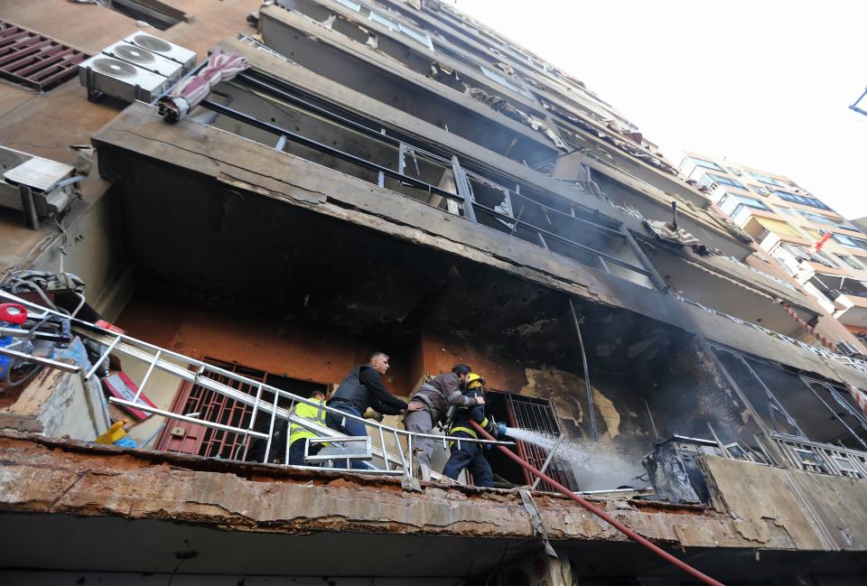 Firefighters extinguish fire on a building at a site of an explosion in the Haret Hreik area in the southern suburbs of the Lebanese capital Beirut