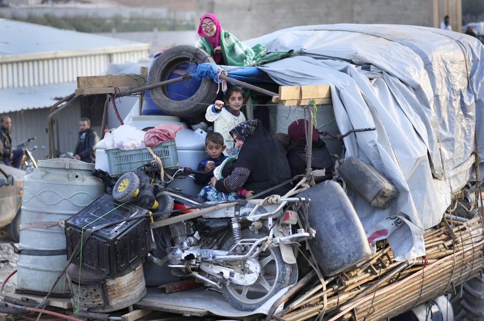 A Syrian refugee family sit on a truck next to their belongings, as they wait at a gathering point to cross the border back home to Syria, in the eastern Lebanese border town of Arsal, Lebanon, Wednesday, Oct. 26, 2022. Several hundred Syrian refugees boarded a convoy of trucks laden with mattresses, water and fuel tanks, bicycles – and, in one case, a goat – Wednesday morning in the remote Lebanese mountain town of Arsal in preparation to return back across the nearby border. (AP Photo/Hussein Malla)