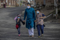 A Kashmiri man along with his children walks on a deserted road, as Kashmiris marked Eid during lockdown to curb the spread of coronavirus in Srinagar, Indian controlled Kashmir, Thursday, May 13, 2021. (AP Photo/ Dar Yasin)