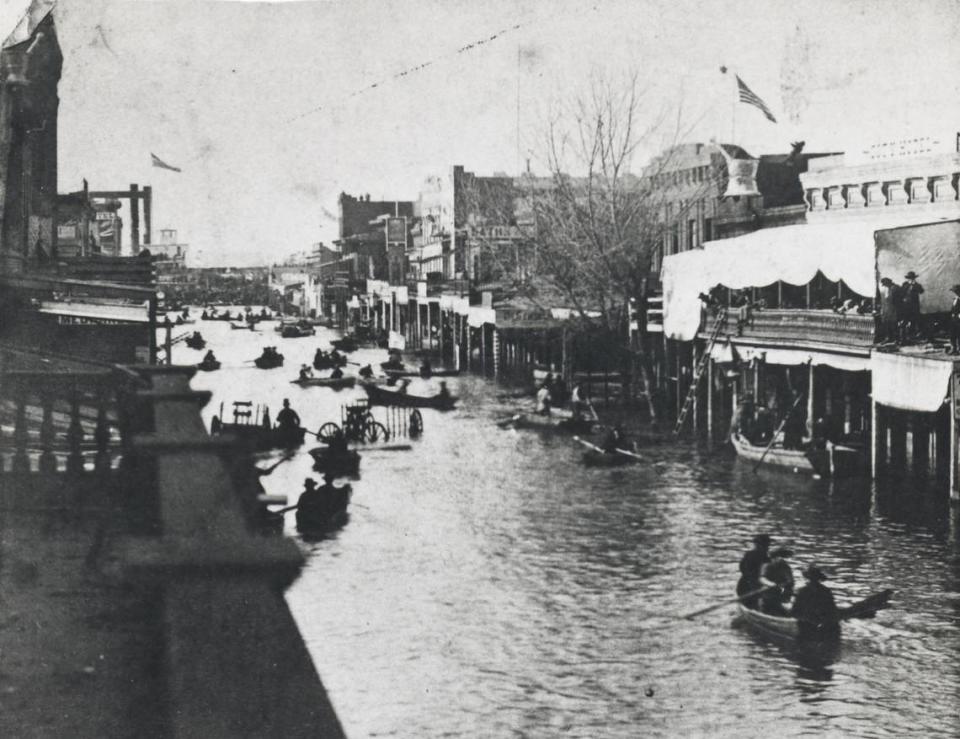 Residents traverse K Street in Sacramento after the flood of 1862.