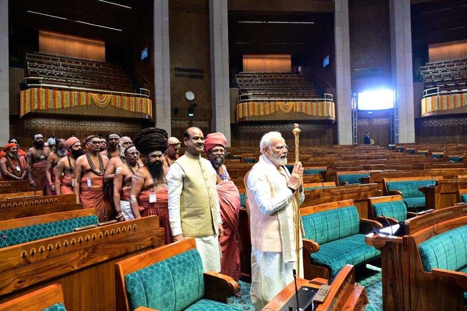 Narendra Modi carries the royal golden sceptre to be installed near the speaker’s chair in the new parliament building (AP)