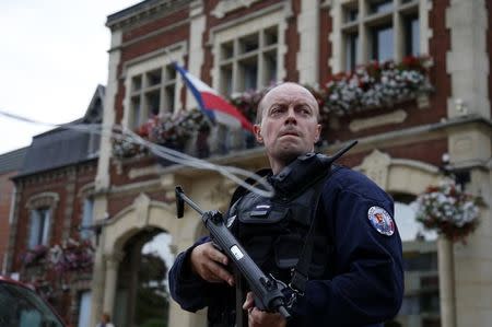 A policeman secures a position in front of the city hall after two assailants had taken five people hostage in the church at Saint-Etienne-du -Rouvray near Rouen in Normandy, France, July 26, 2016. REUTERS/Pascal Rossignol