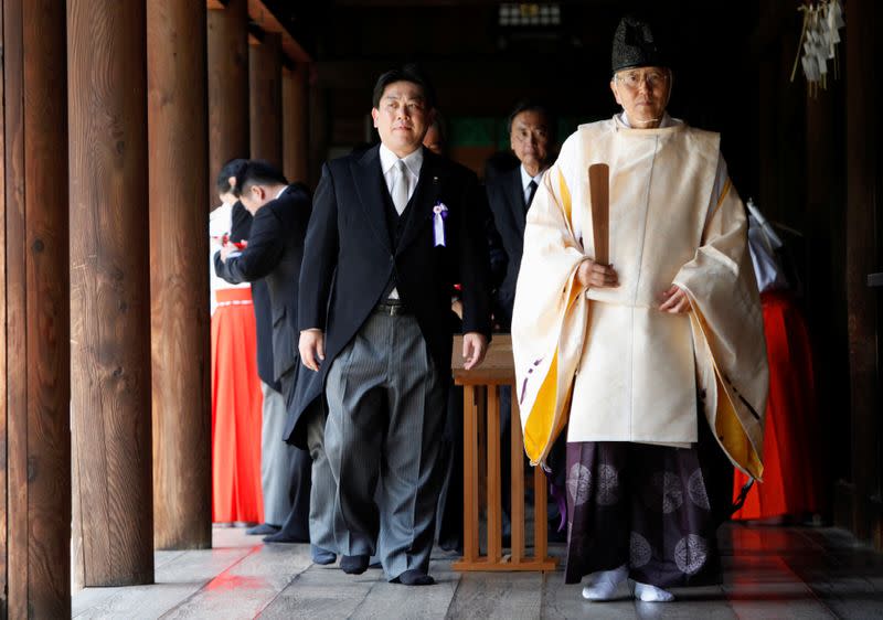 FILE PHOTO: Japan's Land, Infrastructure, Transport and Tourism Minister Hata and other lawmakers are led by a Shinto priest after offering prayers to war dead at Yasukuni Shrine in Tokyo