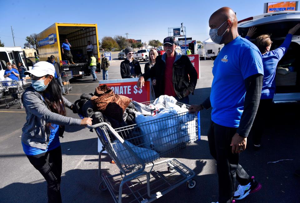 Volunteers cart away bags of donated clothing and other items after unloading them from a vehicle outside of Arrow Ford for Friday's Mission Thanksgiving on Nov. 19.