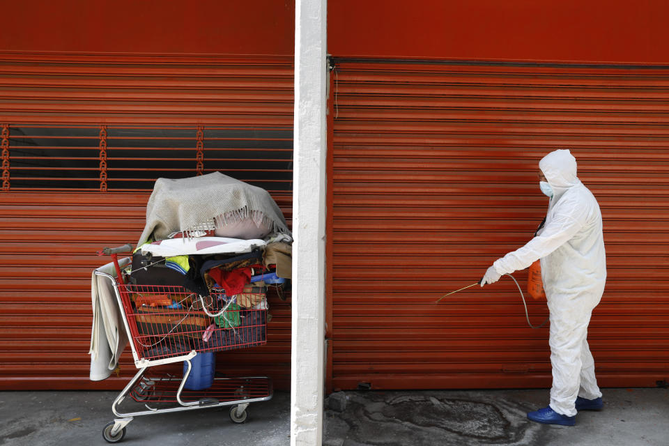 Edwin Monroy, 23, an employee of the capital's Ministry of Inclusion and Social Wellbeing, SIBISO, sprays a disinfectant solution on the ground in an area where homeless men and women often sleep during the night, outside the Basilica of Our Lady of Guadalupe in Mexico City, Wednesday, April 8, 2020. To combat the spread of the novel coronavirus, SIBISO has ramped up the activity of their mobile health clinic catering to the homeless and has begun disinfecting areas where many sleep. (AP Photo/Rebecca Blackwell)