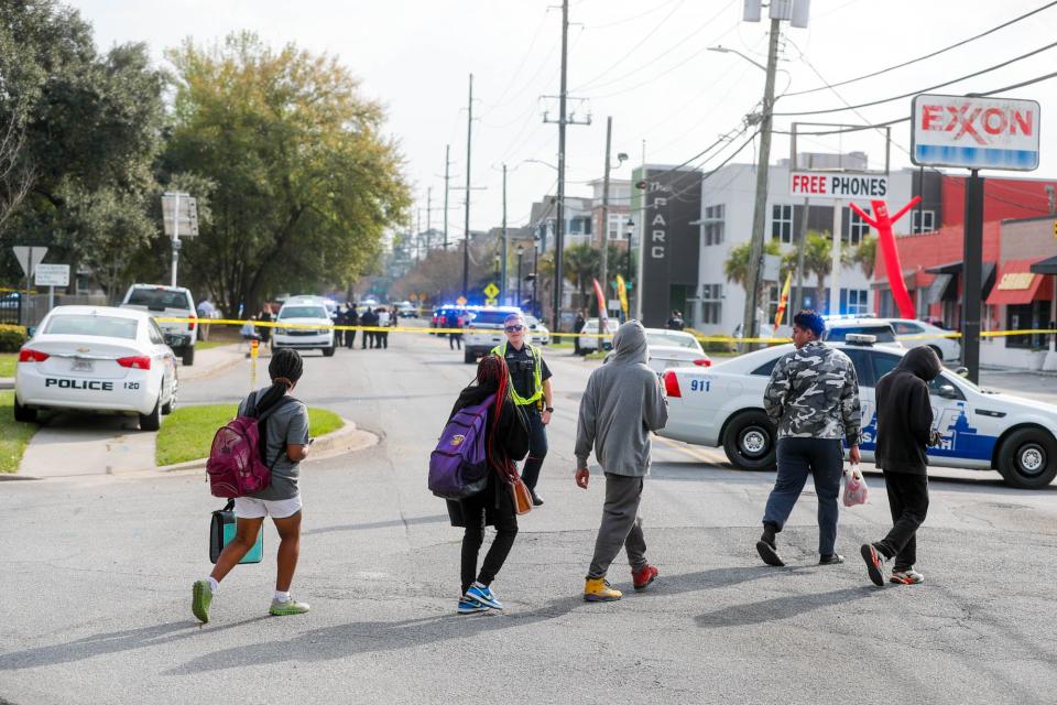 Students walk past as police investigate after a Savannah High student was shoot on Wednesday March 1, 2023 after leaving school.