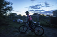 Veronika Tkachenko, 7, rides a bicycle in the yard of her house in the recently retaken town of Izium, Ukraine, Sunday, Sept. 25, 2022. (AP Photo/Evgeniy Maloletka)