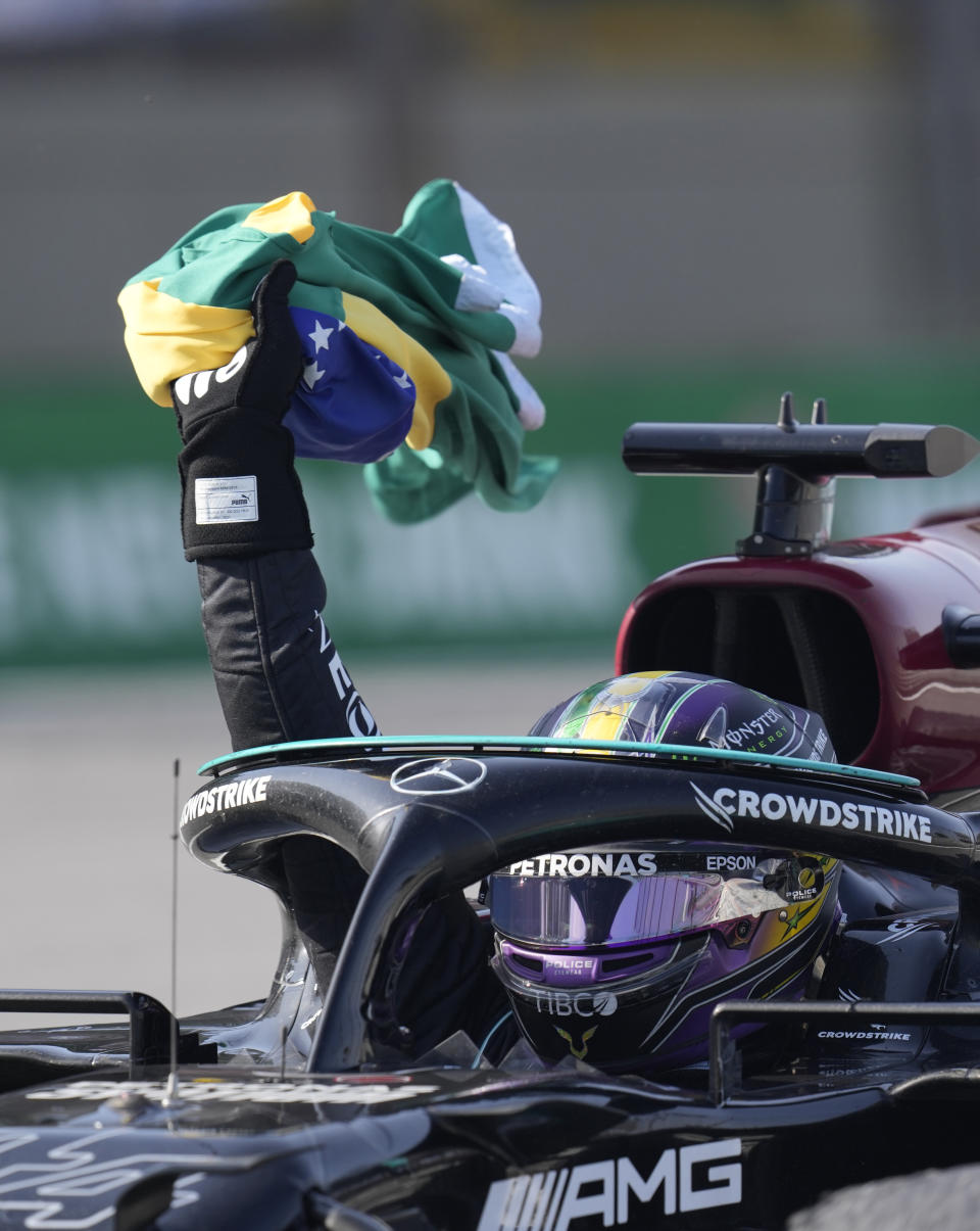 Mercedes' Lewis Hamilton holds a Brazilian flag as he celebrates wining the Brazilian Formula One Grand Prix at the Interlagos race track in Sao Paulo, Brazil, Sunday, Nov. 14, 2021. (AP Photo/Andre Penner)