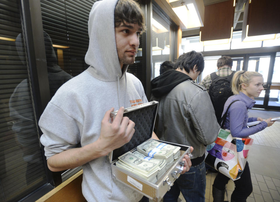 University of Utah student Luke Mughal holds a briefcase full of one-dollar bills as he waits in a long line to pay his tuition at the Student Services Building on the University of Utah campus in Salt Lake City, Utah Tuesday, Jan. 21, 2014. Mughal is paying his tuition in one-dollar bills to protest the high cost of tuition. (AP Photo/The Salt Lake Tribune, Steve Griffin) DESERET NEWS OUT; LOCAL TV OUT; MAGS OUT