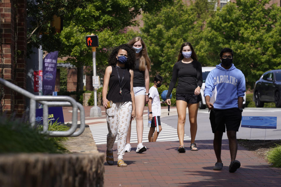 Students wear masks on campus at the University of North Carolina in Chapel Hill, N.C., Tuesday, Aug. 18, 2020. The university announced that it would cancel all in-person undergraduate learning starting on Wednesday following a cluster of COVID-19 cases on campus. (AP Photo/Gerry Broome)
