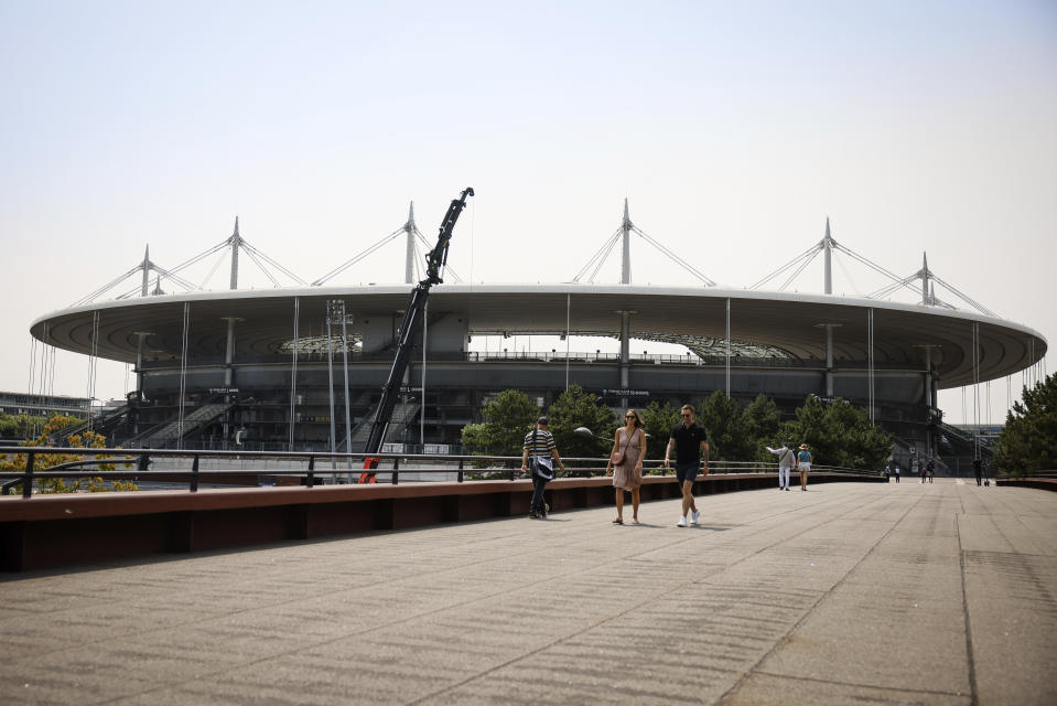 People walk by the Stade de France stadium Monday, July 10, 2023 in Saint-Denis, north of Paris. The stadium will host the athletics and para athletics and and Rugby Sevens in the Paris 2024 games. (AP Photo/Thomas Padilla)