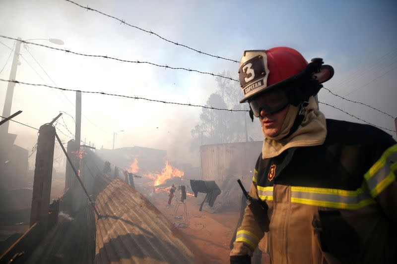 A firefighter walks near flames as a fire continues in Valparaiso