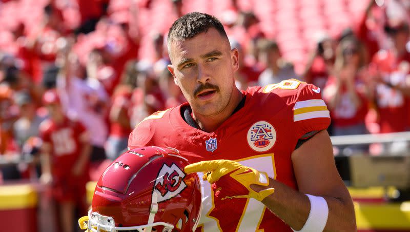 Kansas City Chiefs tight end Travis Kelce points to the Chiefs decal on his helmet as fans cheer during warmups before an NFL football game against the Chicago Bears on Sunday, Sept. 24, 2023 in Kansas City, Mo.