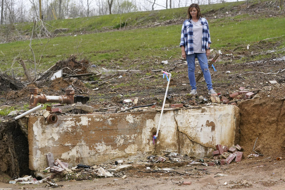 CORRECTS STATE TO KENTUCKY INSTEAD OF TENNESSEE - Chris Bullock looks into the basement area of her former home April 21, 2022, in Dawson Springs, Ky. Bullock, her husband, a son, and family dog survived a massive tornado as it destroyed the home by huddling in a corner of the basement Dec. 10. Four months after the tornado upended her family's lives, Bullock and hundreds of other Kentuckians are arduously reconstructing their pre-storm existence. (AP Photo/Mark Humphrey)