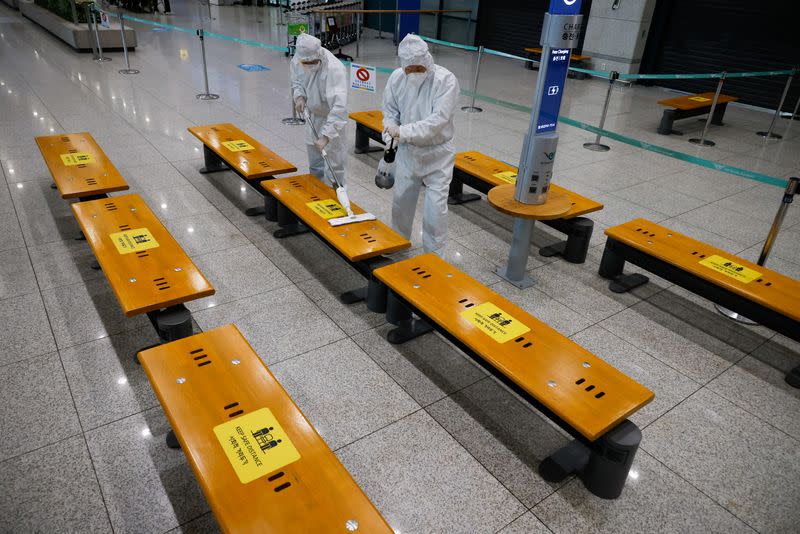 Workers wearing protective gear disinfect an arrival gate at the Incheon International Airport in Incheon