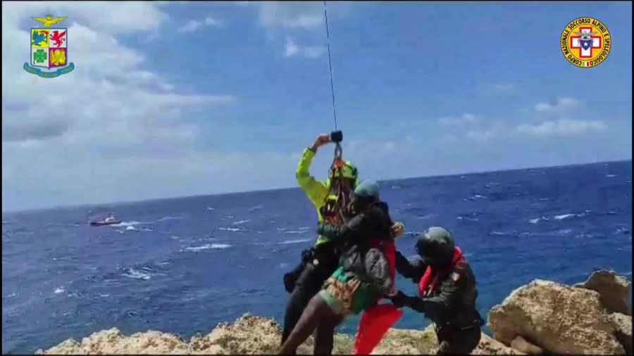 In this picture taken from video distributed on Sunday, Aug. 6, 2023 by the Italian Alpine Rescue squads, a migrant stranded on a rocky reef on the tiny Italian southern island of Lampedusa, Sicily is pluck to safety by helicopter. (Italian Alpine Rescue via AP)