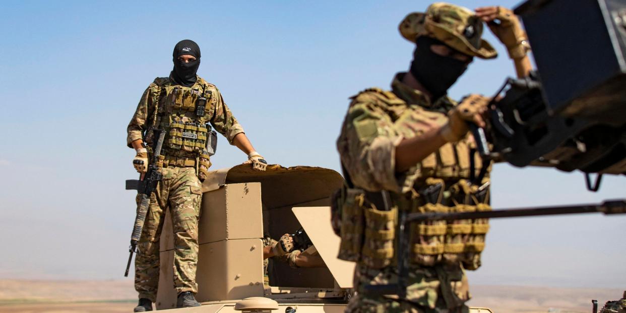 A fighter of the Syrian Democratic Forces (SDF) stands atop a humvee during a joint military exercise with forces of the US-led "Combined Joint Task Force-Operation Inherent Resolve" coalition against the Islamic State (IS) group in the countryside of the town of al-Malikiya (Derik in Kurdish) in Syria's northeastern Hasakah province on September 7, 2022.