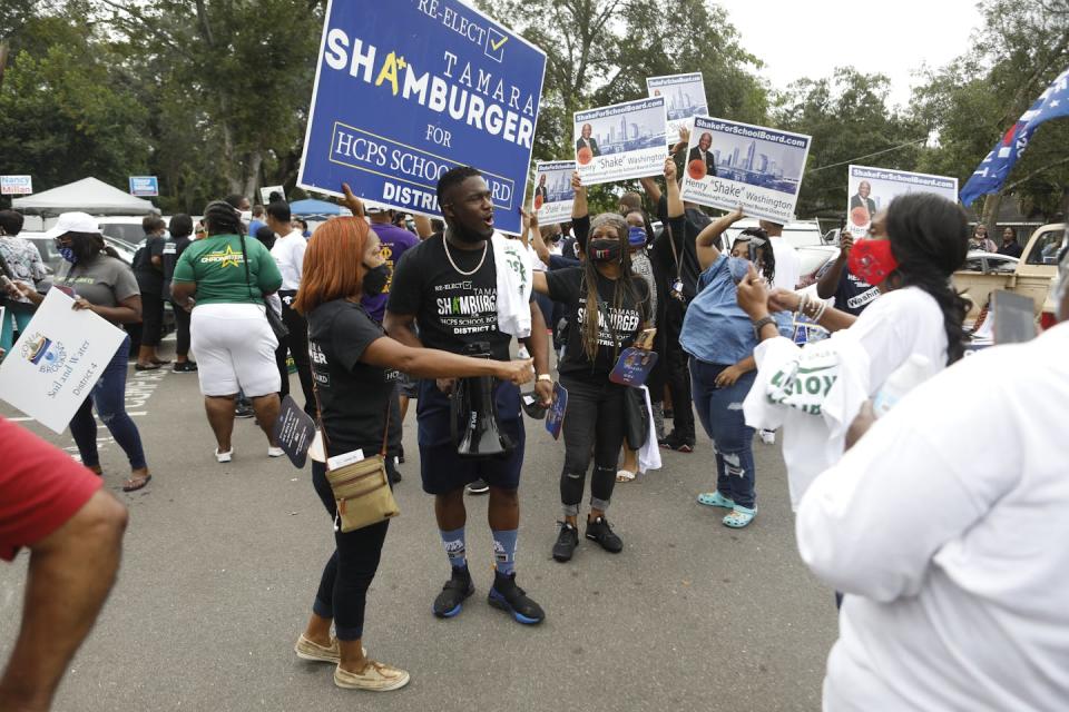 A gathering of people outside, holding signs.