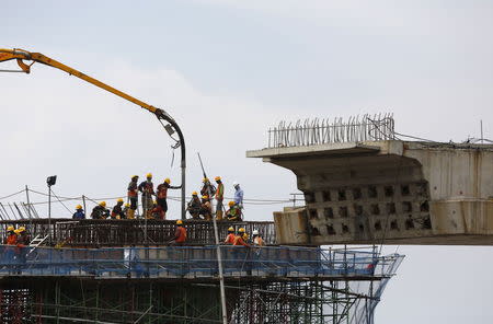 Construction workers pour concrete on a section of an elevated highway under construction in Jakarta December 3, 2015. REUTERS/Darren Whiteside