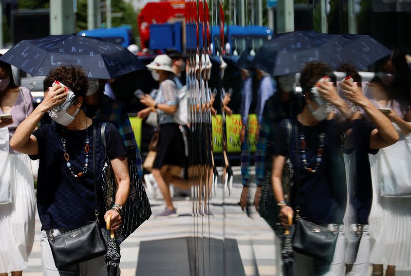 A woman wipes her face as she walks on a street in Tokyo