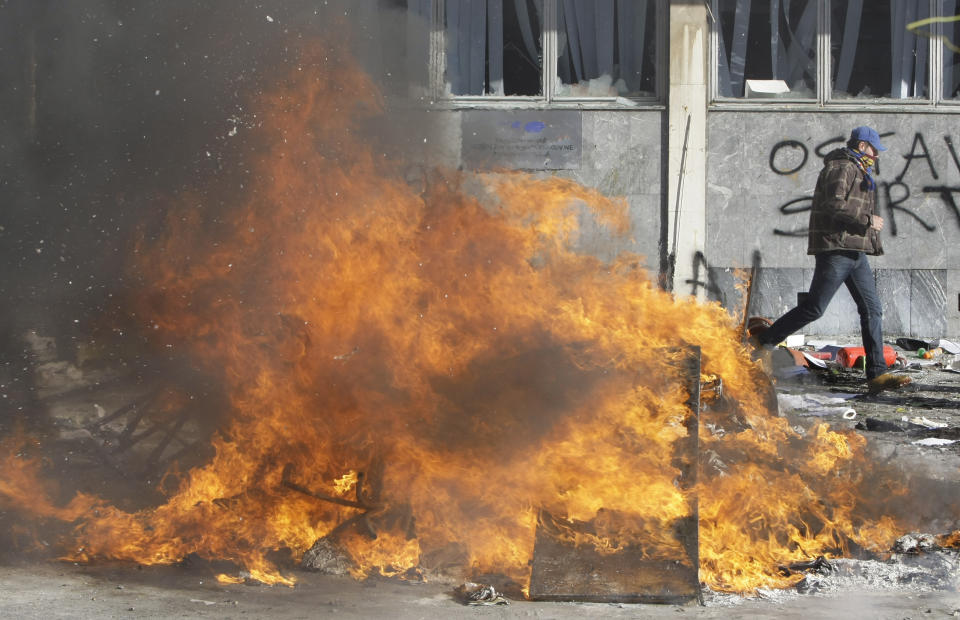 A protester runs from a local government building, during a protest, in the Bosnian town of Tuzla, Friday, Feb. 7, 2014. Bosnian protesters stormed and set ablaze local government buildings in three Bosnian cities on Friday in fury over unemployment and rampant corruption. At least 90 people were injured. (AP Photo/Amel Emric)