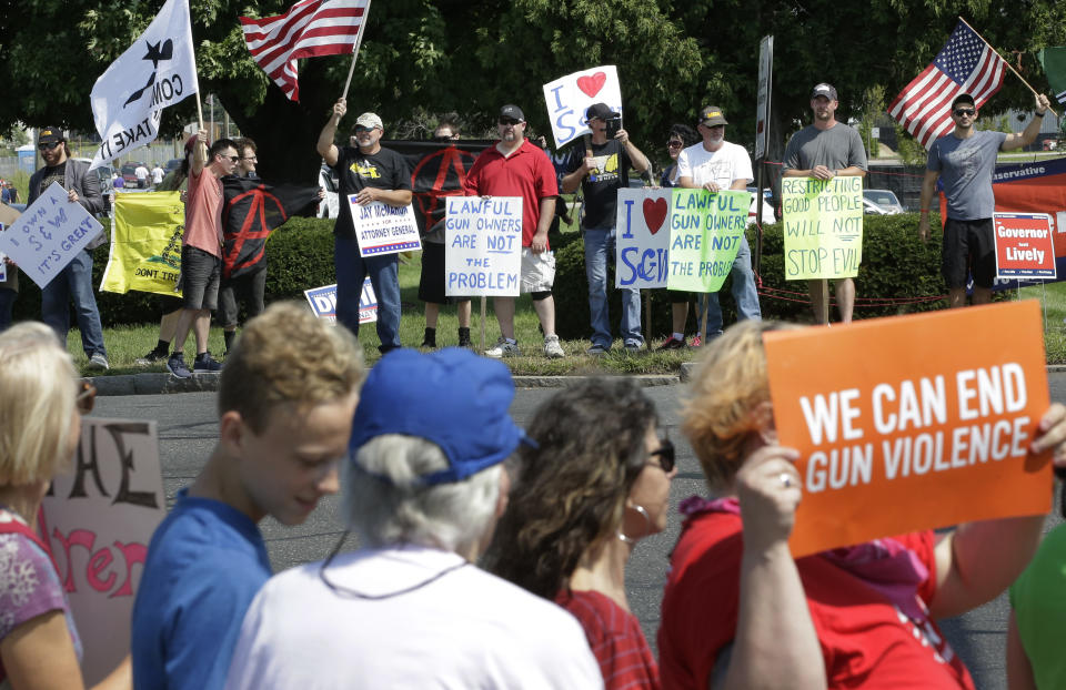 Demonstrators supporting gun law reforms, foreground, walk on the opposite side of the road from counter protesters supporting Second Amendment rights, behind, near the headquarters of gun manufacturer Smith & Wesson, Sunday, Aug. 26, 2018, in Springfield, Mass. The 50-mile march supporting gun law reforms, began Thursday, Aug. 23, 2018, in Worcester, Mass., and ended Sunday, in Springfield, with a rally near the headquarters of the gun manufacturer. (AP Photo/Steven Senne)