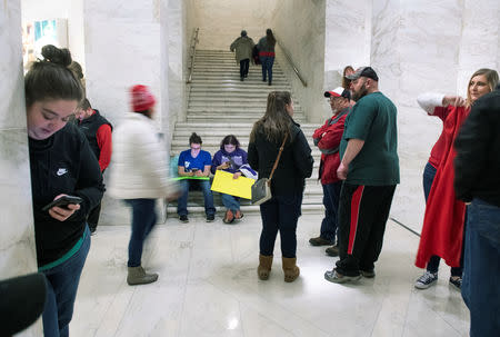 Striking teachers and supporters sit on the stairs inside the Capitol building as they listen to legislative floor discussions where lawmakers rejected a bill that would have opened the first charter schools in the state, in Charleston, West Virginia, U.S., February 19, 2019. REUTERS/Lexi Browning